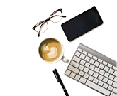Tastatur, Smartphone, Brille und Kaffee auf einem Schreibtisch